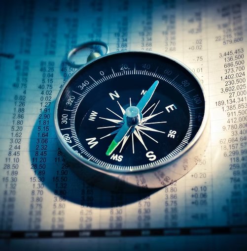 A compass lying on a printed financial table.